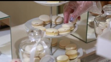 Şenlikli masa hizmet polietilen eldiven Kadın garson, lezzetli beyaz macaroons koyar, eller yakın çekim.