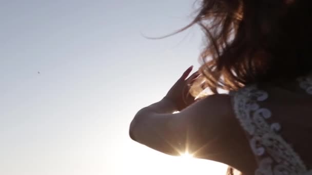 여자는 일몰에 그녀의 손바닥을 태양을 클로즈업 — 비디오