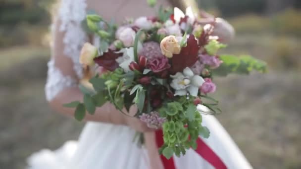 屋外でバラとユーストマスの美しい花の花束を保持する花嫁 — ストック動画