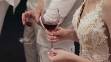 Gelin ve Damat restoranda bir düğün ziyafetinde şarap kadehleri tutar. Eller yakın çekim.