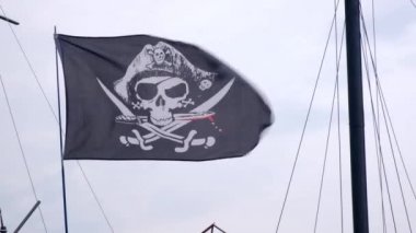 Korsan bayrağı Jolly Roger rüzgarlı bir günde mavi gökyüzü arka plan üzerinde bir gemi direği asılı.