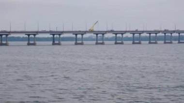 Bir şehirde nehir üzerinde büyük beton köprü üzerinde sürüş arabalar. Kamyon vinç onarım yapar.