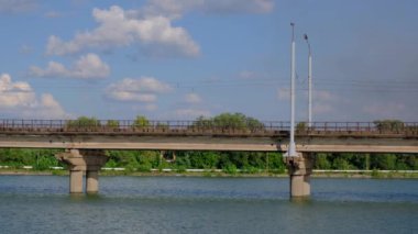 Mavi bulutlu gökyüzü arka planda nehir üzerinde köprü boyunca tramvay hamle.