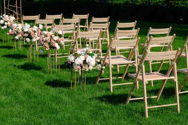 Bir satırda Beyaz ahşap boş sandalyeler ve yeşil çiçekler buketleri