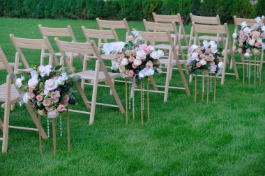 Bir satırda Beyaz ahşap boş sandalyeler ve yeşil çiçekler buketleri