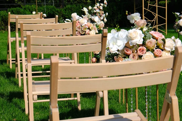 Chaises blanches vides en bois dans une rangée et bouquets de fleurs sur vert — Photo