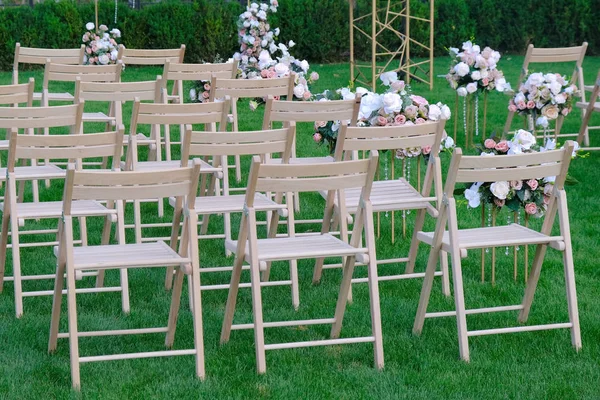Белые деревянные пустые стулья в ряд и букеты цветов на зеленый — стоковое фото