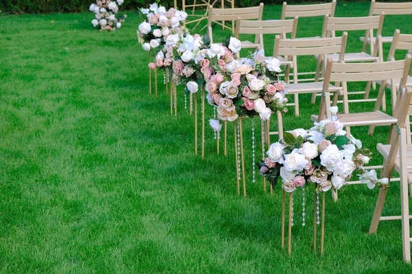 White wooden empty chairs in a row and flowers bouquets on green — Stock Photo, Image