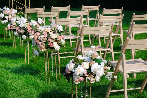 White wooden empty chairs in a row and flowers bouquets on green — Stock Photo, Image