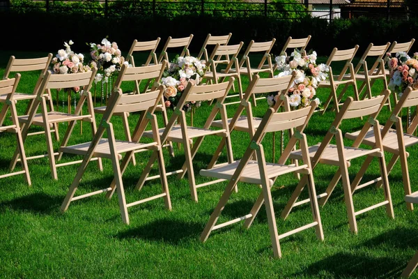 Білі дерев'яні порожні стільці в ряд і букети з квітів на зеленому — стокове фото