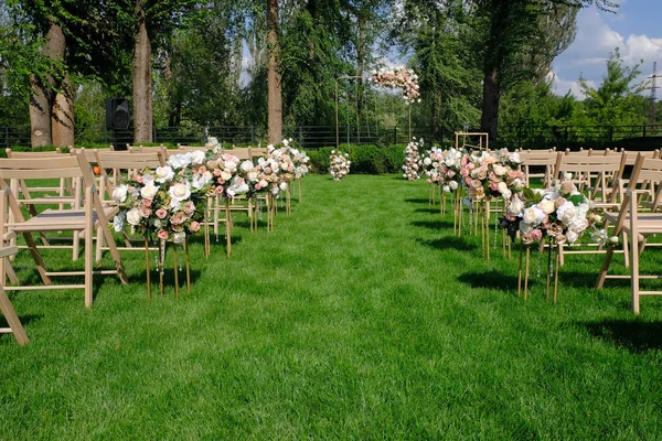 Λευκές ξύλινες κενές καρέκλες σε μια σειρά και λουλούδια Μπουκέτα στο πράσινο — Φωτογραφία Αρχείου