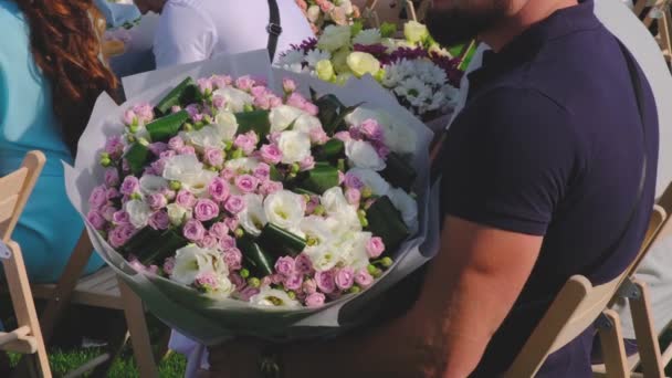 Gäster med en blomma buketter sitter på en bröllopsceremoni — Stockvideo