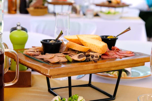 Tasty smoked cutted bacon on a wooden tray on a banquet table in — Stock Photo, Image