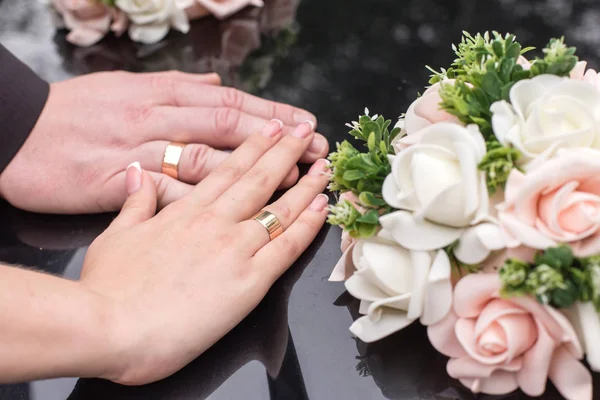 Mains de mariée et de marié avec des anneaux de mariage sur une surface d'un bl — Photo