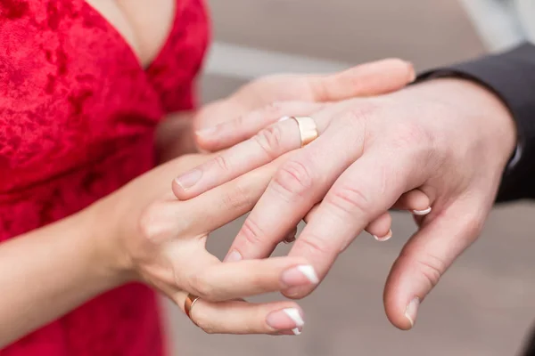 Noiva vestida com um vestido vermelho sexy coloca um anel para o dedo do noivo — Fotografia de Stock