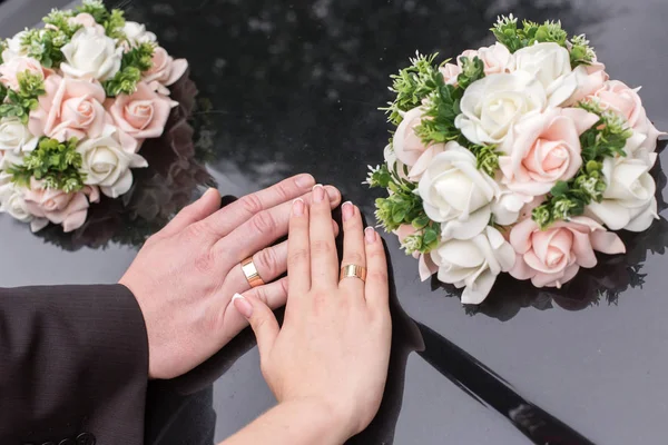 Mains de mariée et de marié avec des anneaux de mariage sur une surface d'un bl — Photo