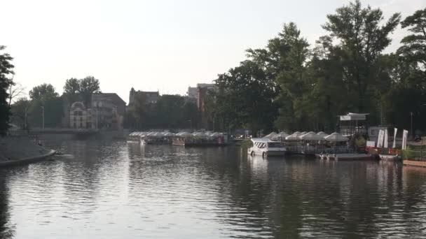 Vatten café, båtar på en flod, spårvagn på en stadsgata vid solnedgången. — Stockvideo