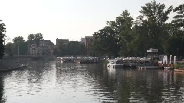 Café acuático, barcos en un río, tranvía en una calle de la ciudad al atardecer . — Vídeo de stock