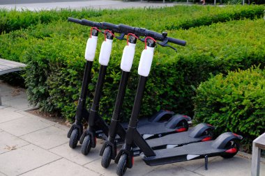 Şehir kaldırımında arka arkaya park edilmiş dört elektrikli scooter.