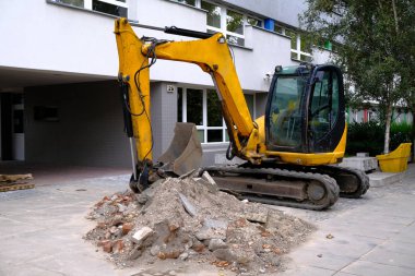 Şehir merkezinde bir Kaldırım üzerinde Sarı Küçük Ekskavatör çalışması.