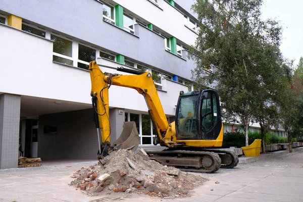 黄色小型挖掘机在市中心的人行道上工作. — 图库照片