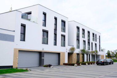 İki garajı ve arabaları olan modern beyaz bir bina..