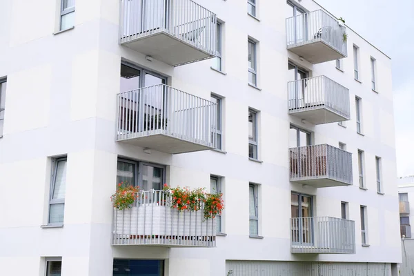 Rote Blumen blühen auf dem Balkon eines modernen Mehrfamilienhauses. — Stockfoto