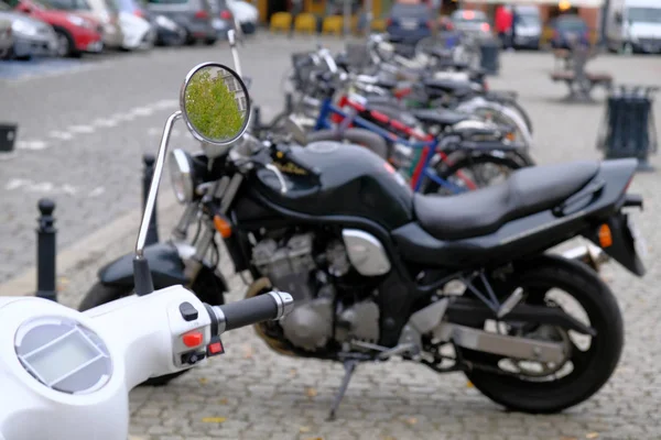 Vit urban scooter och grupp av kraftfulla svarta motorcyklar är — Stockfoto