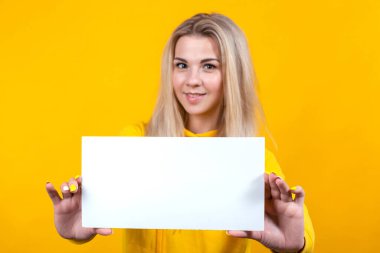 Mesajın burada. Güzel beyaz bir kadın reklam için boş tahta tutuyor. Stüdyo portresi. Sarı arka planda güzel bir kız..