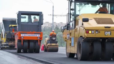 Şehir caddesinde çalışan yol silindirleri. Yeni otoyolun yapımında ağır endüstriyel makineler.