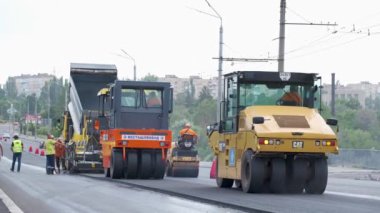 Şehir caddesinde çalışan yol silindirleri. Yeni otoyolun yapımında ağır endüstriyel makineler.