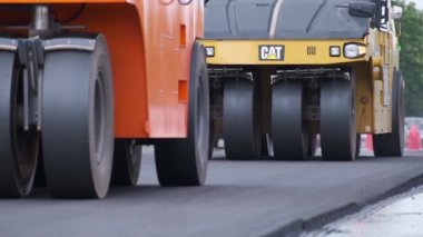 Şehir caddesinde çalışan yol silindirleri. Yeni otoyolun yapımında ağır endüstriyel makineler.