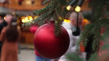 Kırmızı bir Noel balosu ve kız kıza yakın bir şehir panayırında doğal bir yılbaşı ağacına asılıyor.,