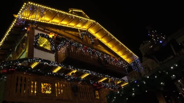 Människor vilar på en balkong dekorerad jul träbyggnad — Stockvideo