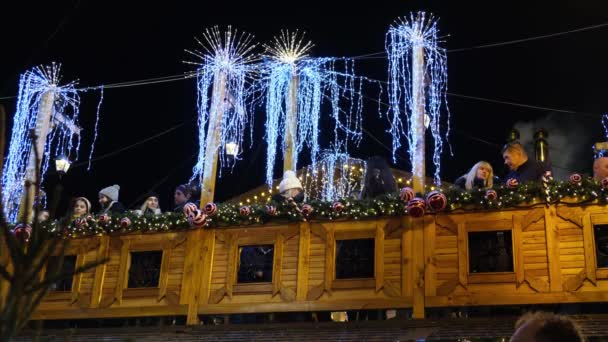 Люди п'ють потовчене вино на Різдвяному ярмарку на дерев'яному оздобленому балконі.. — стокове відео