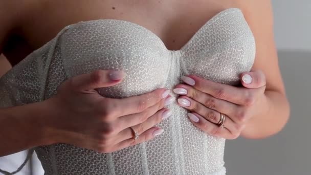 Κοντινό πλάνο νύφες χέρια υποστήριξη στήθος της, ενώ φορώντας ένα νυφικό. — Αρχείο Βίντεο