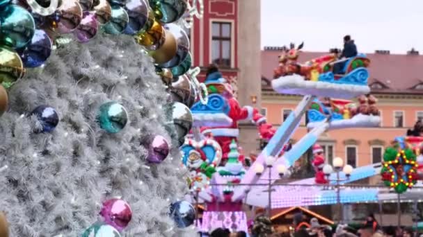 Menschen fahren an einem Wintertag auf einem geschmückten Weihnachtsmarkt in einer Stadt mit einem Karussell. — Stockvideo