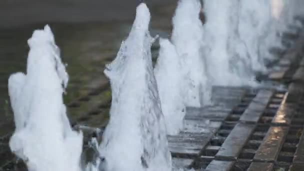 Stadtpflaster mit Springbrunnen in einer Reihe. Kleines Mädchen spielt in einem Wasserbach — Stockvideo