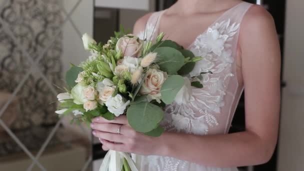 Mooie jonge bruid met bruidsboeket van pastelrozen, in een hotel. — Stockvideo