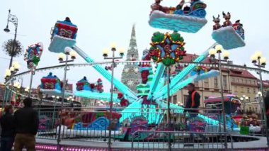 İnsanlar süslü bir Noel fuarında atlıkarıncaya biniyorlar..