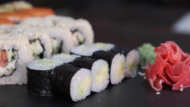 Sushi Rolls Szett Tonhallal Lazaccal Uborkával Avokádóval Forgó Asztalon Fekete — Stock videók