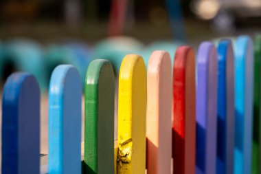 Tahta, gökkuşağı renginde, güneşli, sıcak bir çitin üzerinde.