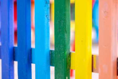 Tahta, gökkuşağı renginde, güneşli, sıcak bir çitin üzerinde.