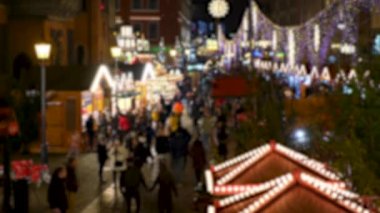 İnsanlar Noel ışıkları arasında dinleniyor, yürüyor, yeni yıl pazarını fareliyor ahşap binalar süslüyor. Gece sahnesi. Üst görünüm.