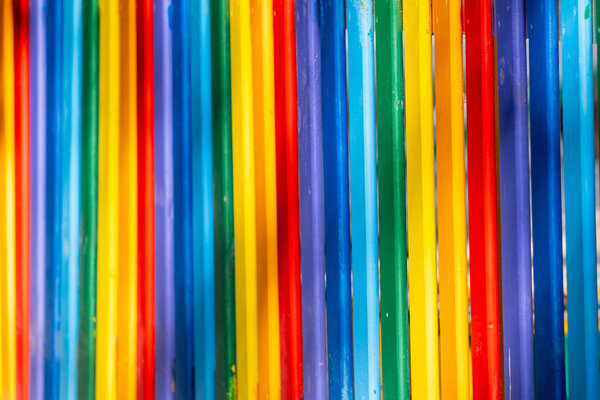 Part of wooden, rainbow colorful painted fence  on a sunny hot day outdoors. Vivid bright background.