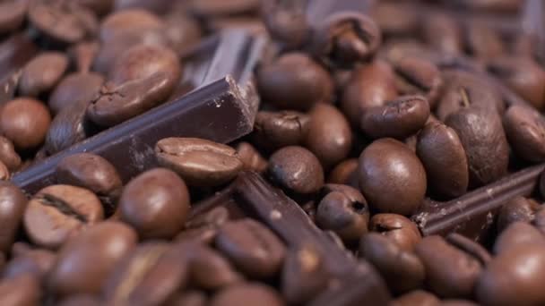 烤咖啡豆和巧克力在旋转桌子上的特写 香味浓郁的咖啡粒和甜巧克力片都在转动 — 图库视频影像