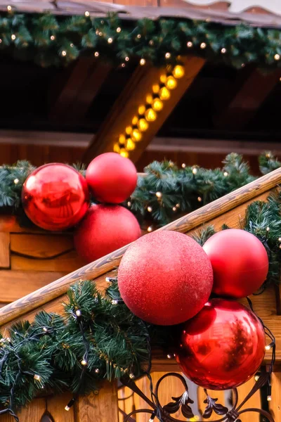 Wooden Retro Restaurant Building Decorated of Artificial Fir Tree with Lighting Garland and many Red Christmas Bells at Winter Day, no Snow.