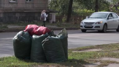 Şehir caddesinde çöp dolu birkaç plastik torba. Arabalar yol boyunca gider. Şehir trafiği. Ekolojik sorunlar. KRYVYI RIH, UKRAINE - Ekim 2020.