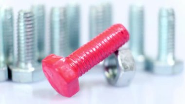 Galvanize metalik vidalardan oluşan bir grup yakın plan, biri pembe renkli. Herkes gibi değil. Beyaz zemin üzerinde paslanmaz çelik cıvatalar izole.