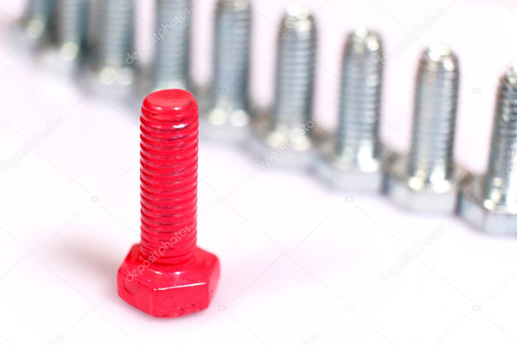 Close-up of pink bolt n a group of galvanized metallic screws. Leadership, individuality, originality concept. Stainless steel bolts isolated on white background.